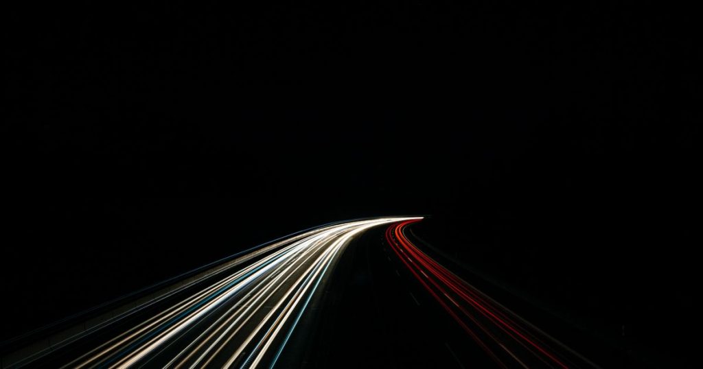Long-exposure light trails on a highway at night, conveying speed