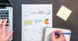 Analytics charts and performance reports on a desk beside a laptop