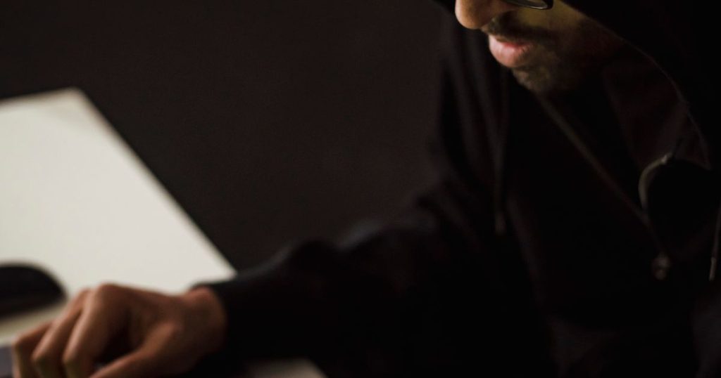 Hands using a laptop and smartphone in the dark