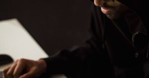 Hands using a laptop and smartphone in the dark